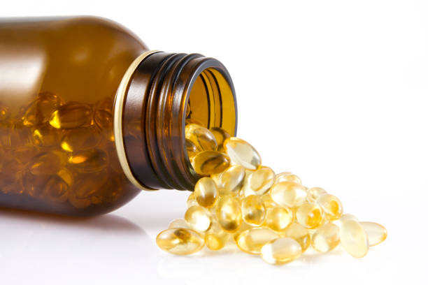 Fish Oil Capsules Spilled omega oil capsules on white background vitamin d stock pictures, royalty-free photos & images