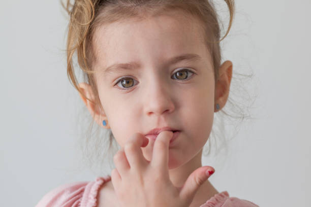 istock Little girl looking at camera biting fingernails 1030477528