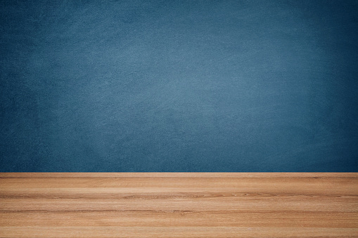 Empty school desk against blue chalkboard background