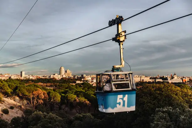Cable car cabin in Madrid on background of residential area and houses rides over park