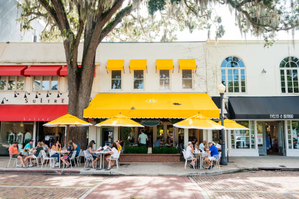 Restaurants and Shops Line Park Avenue in Downtown Winter Park Florida USA This is a horizontal, color photograph Park Avenue in downtown Winter Park, Florida. People dine at outside tables under umbrellas by the sidewalk. orlando florida photos stock pictures, royalty-free photos & images