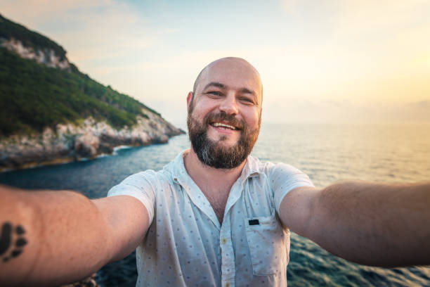 Cheerful bearded man taking selfie outdoors