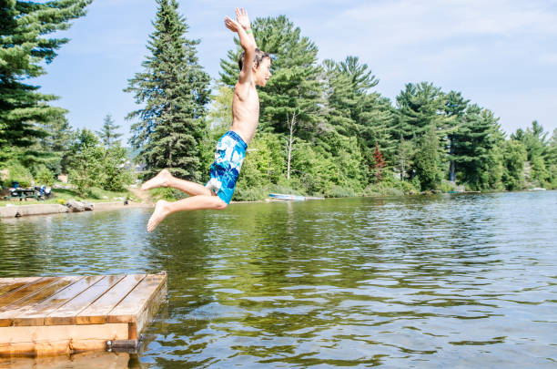 istock Young boy jumping in a lake from the pier during summer day 1030492304