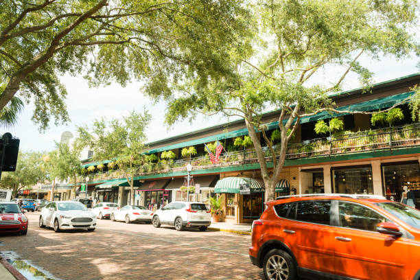 Cars Drive on Tree Shaded Park Avenue in Downtown Winter Park Florida USA This is a horizontal, color photograph Park Avenue in downtown Winter Park, Florida. Cars drive along the tree shaded brick road. winter park florida stock pictures, royalty-free photos & images