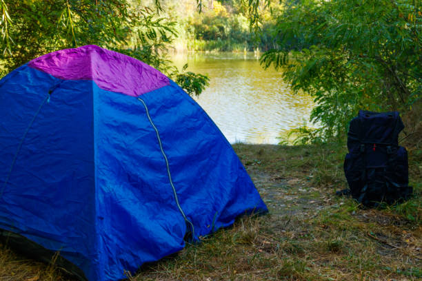 istock Blue camping tent and backpack in forest near a river 1030496740