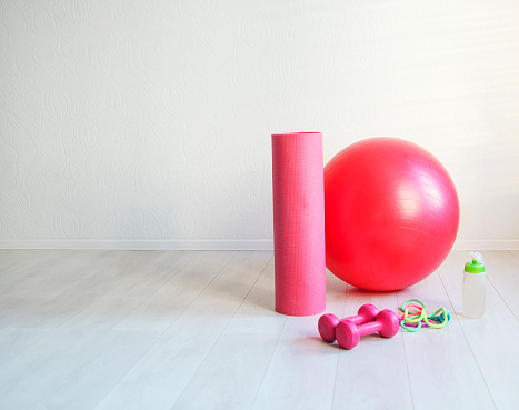 Sports equipment. Gym ball, yoga mat, skipping rope, dumbbell  and bottle of the water closeup on white background