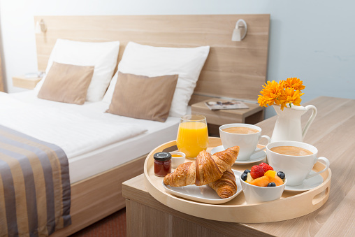 A woman enjoying her breakfast in bed of croissants and orange juice