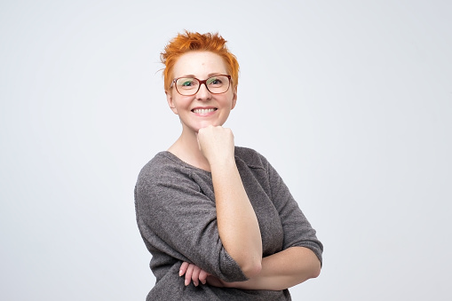 Portrait of beautiful mature woman with red hair standing and smiling with arms crossed