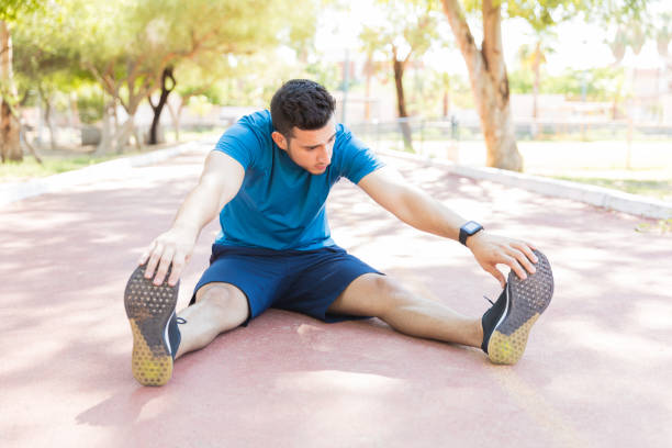 istock Flexible Man Touching Toes While Warming Up In Park 1030515094