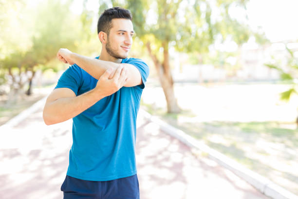 istock Male Runner Stretching Arm Before Workout In Park 1030515480