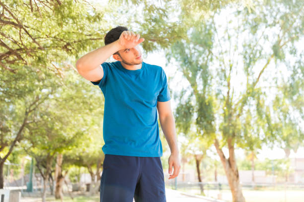 istock Tired Man Wiping His Forehead After Jogging In Park 1030518338