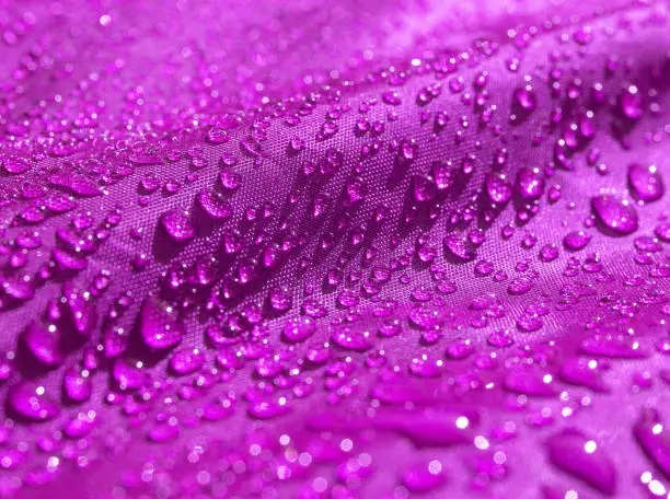 Photo of Purple waterproof fabric with waterdrops close up