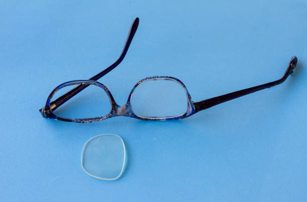 istock Broken eyeglasses, burned plastic frame, damaged beyond repair,  on blue background, 1030522598