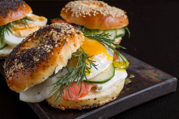 istock bagels with egg and cucumber on black background. 1030530828