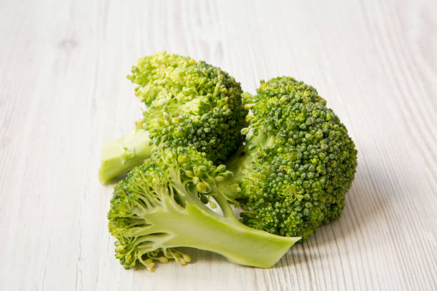 istock Raw broccoli on white wooden surface, side view. 1030533338
