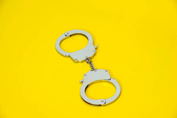 istock Metal handcuffs isolated on yellow background 1030533740