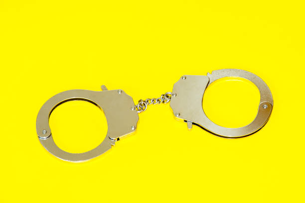 istock Metal handcuffs isolated on yellow background 1030534198