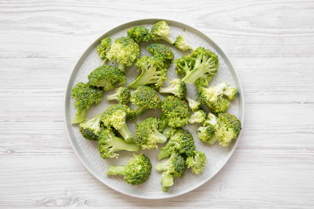 istock Freshly cut raw broccoli on gray plate over white wooden surface, overhead view. Flat lay, from above, top view. 1030537164