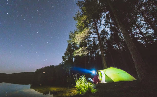 istock Camper sitting by tent under the night sky. 1030543524