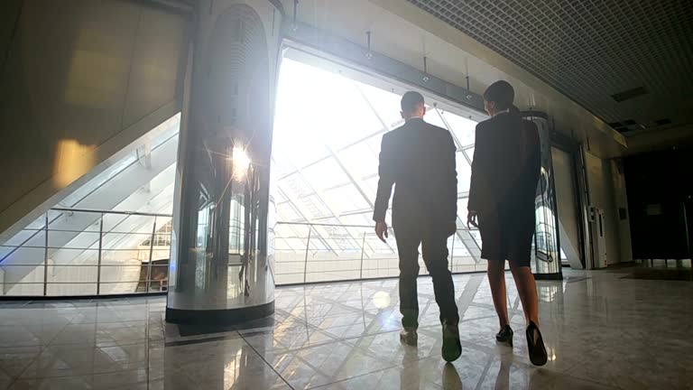 The businessman and a businesswoman walking in the office center. slow motion