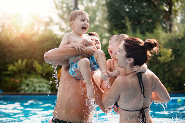 Little boy with Down syndrome having fun in the swimming pool with his family stock photo