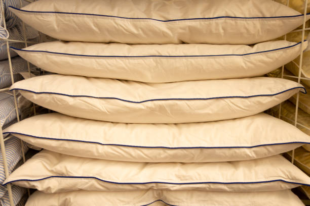 istock Stack of warm plaid and pillows on white shelf against striped wall background 1030558312