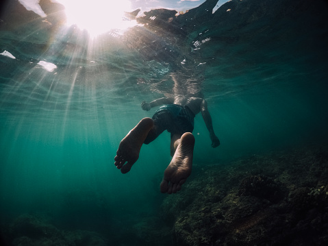 Man swimming towards the sun (underwater photo)