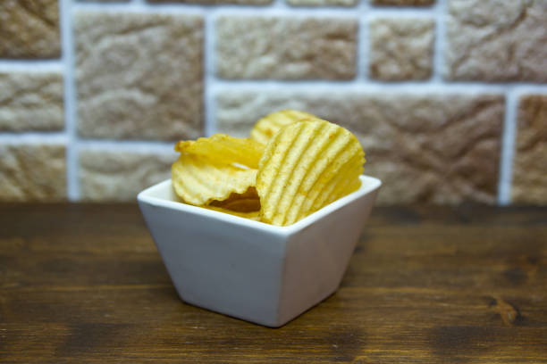 istock Corrugated chips inside square bowl on a wooden table viewed from close up 1030572634