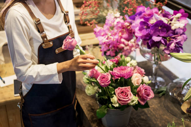 istock Midsection Of Florist Putting Rose In Bucket On Table 1030573336