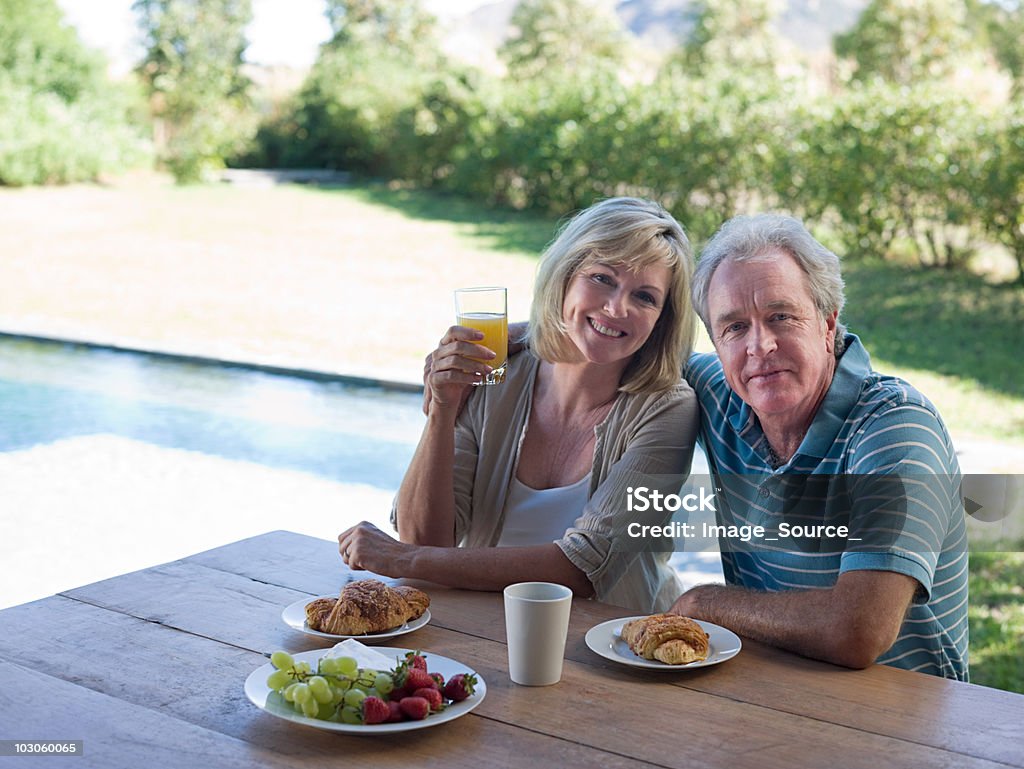 Coppia, avere la colazione in giardino - Foto stock royalty-free di 55-59 anni