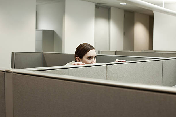 mujer esconde detrás de cubículo de oficina - deshonestidad fotos fotografías e imágenes de stock