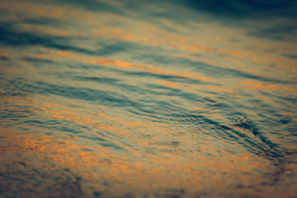 istock Glow of the Sunset Mirrored on Teal Blue Rippling Water 1030608008