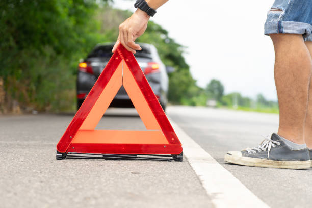 istock A car breakdown alongside the road, man sets the warning triangle.
Driver putting out a traffic warning sign - broken car on the road.
man having car trouble on the country road, putting warning triangle on asphalt road. Emergency stop concept. 1030622730