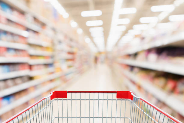 istock Supermarket aisle blurred background with empty red shopping cart 1030623720