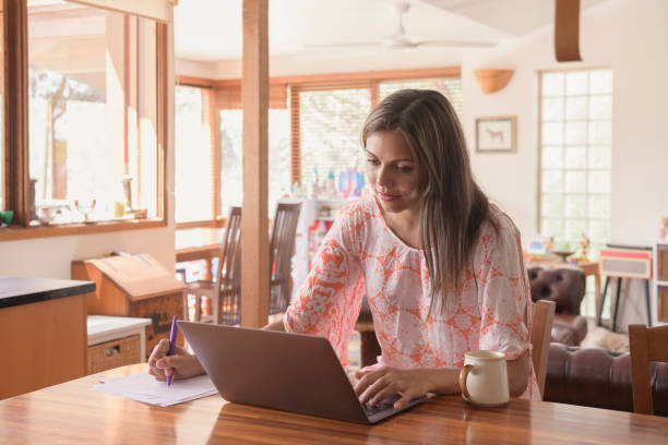 istock Young woman working at home on laptop and making notes 1030629830