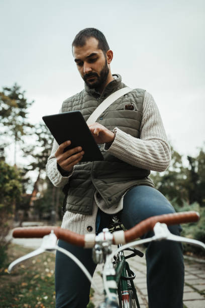 istock Close-up of a man with a bicycle using digital tablet in the park 1030632008