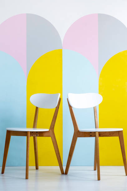 Two chairs set on a patterned wall with yellow accents. Real photo