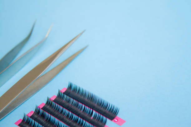 istock tools for Eyelash Extension Procedure. Two tweezers with false lashes on blue background. copyspace mockup - Beauty and fashion concept 1030642028