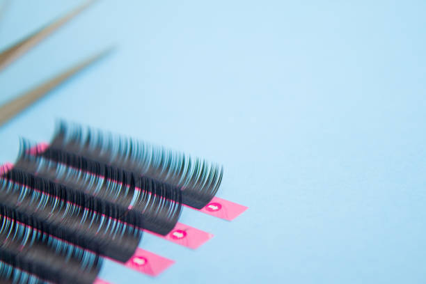 istock tools for Eyelash Extension Procedure. Two tweezers with false lashes on blue background. copyspace mockup - Beauty and fashion concept 1030642072