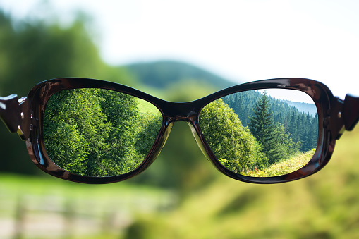Creative concept about poor vision. Landscape focused in glasses lenses over the photo blurred