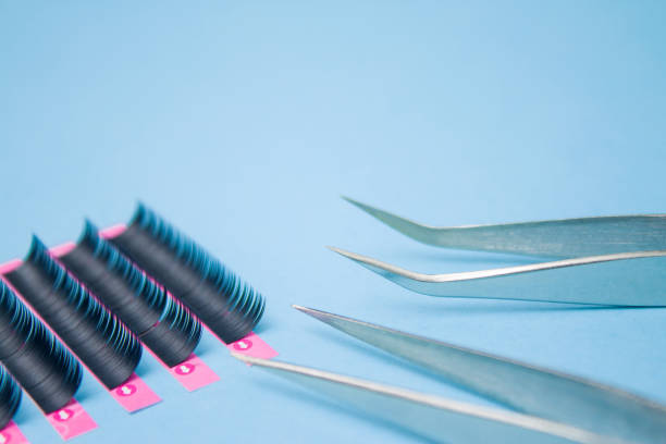 istock tools for Eyelash Extension Procedure. Two tweezers with false lashes on blue background. copyspace mockup - Beauty and fashion concept 1030642288