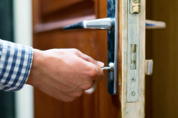 close up person hand in checkered shirt opens door  using keys