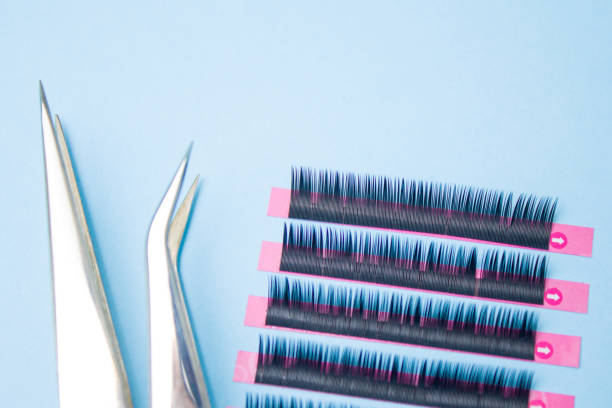 istock tools for Eyelash Extension Procedure. Two tweezers with artificial black lashes on blue background. copyspace mockup - Beauty and fashion concept 1030643198