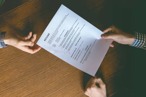 Photo of top overhead directly above view of employee hiring person and examine the resume on the office table