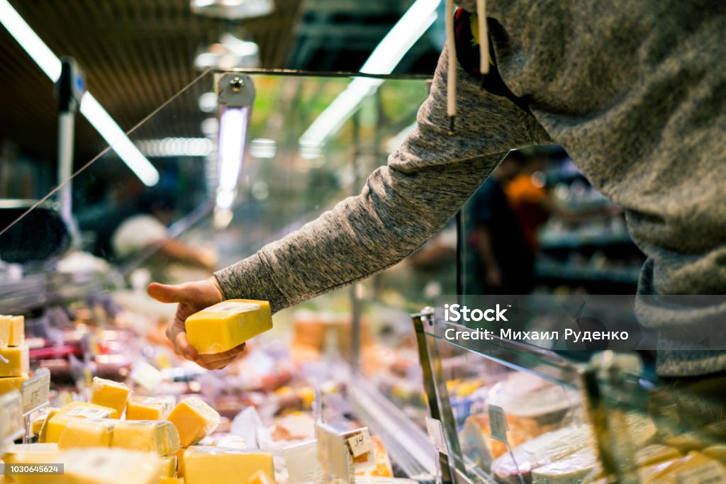 close up person hand buying cheese in  store close up person hand buying cheese in the  store Cheese Stock Photo