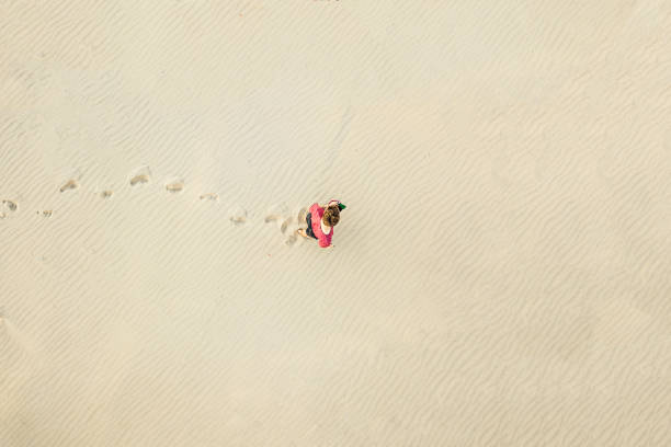 vista aérea superior do jovem solitária caminhada no deserto sobre a textura de areia. conceito perdido - lost beach - fotografias e filmes do acervo