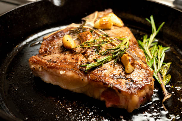 istock Sizzling T-Bone Steak on a cast iron skillet with herbs and Garlic 1030653696