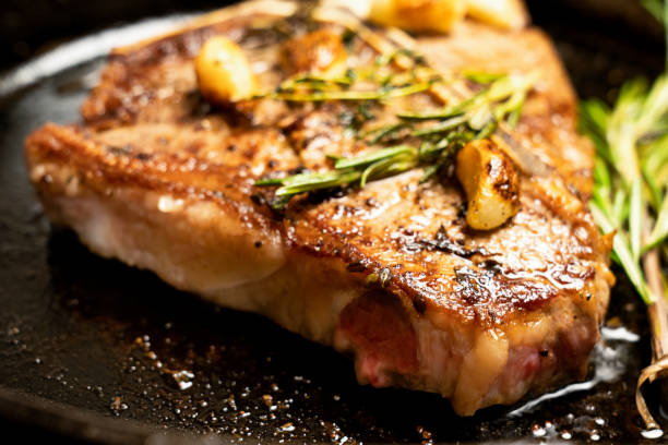 istock Sizzling T-Bone Steak on a cast iron skillet with herbs and Garlic 1030653698