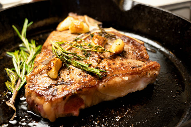 istock Sizzling T-Bone Steak on a cast iron skillet with herbs and Garlic 1030653732