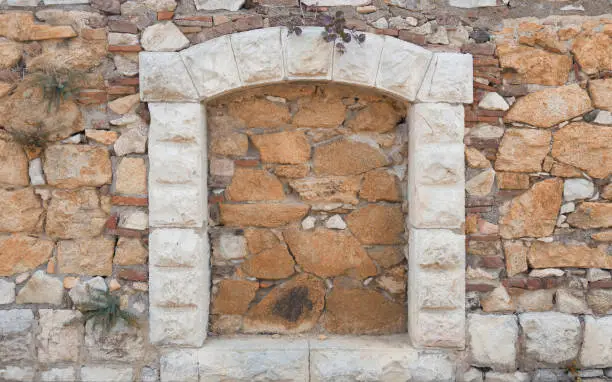 Laid arched window in the stone wall of the house.